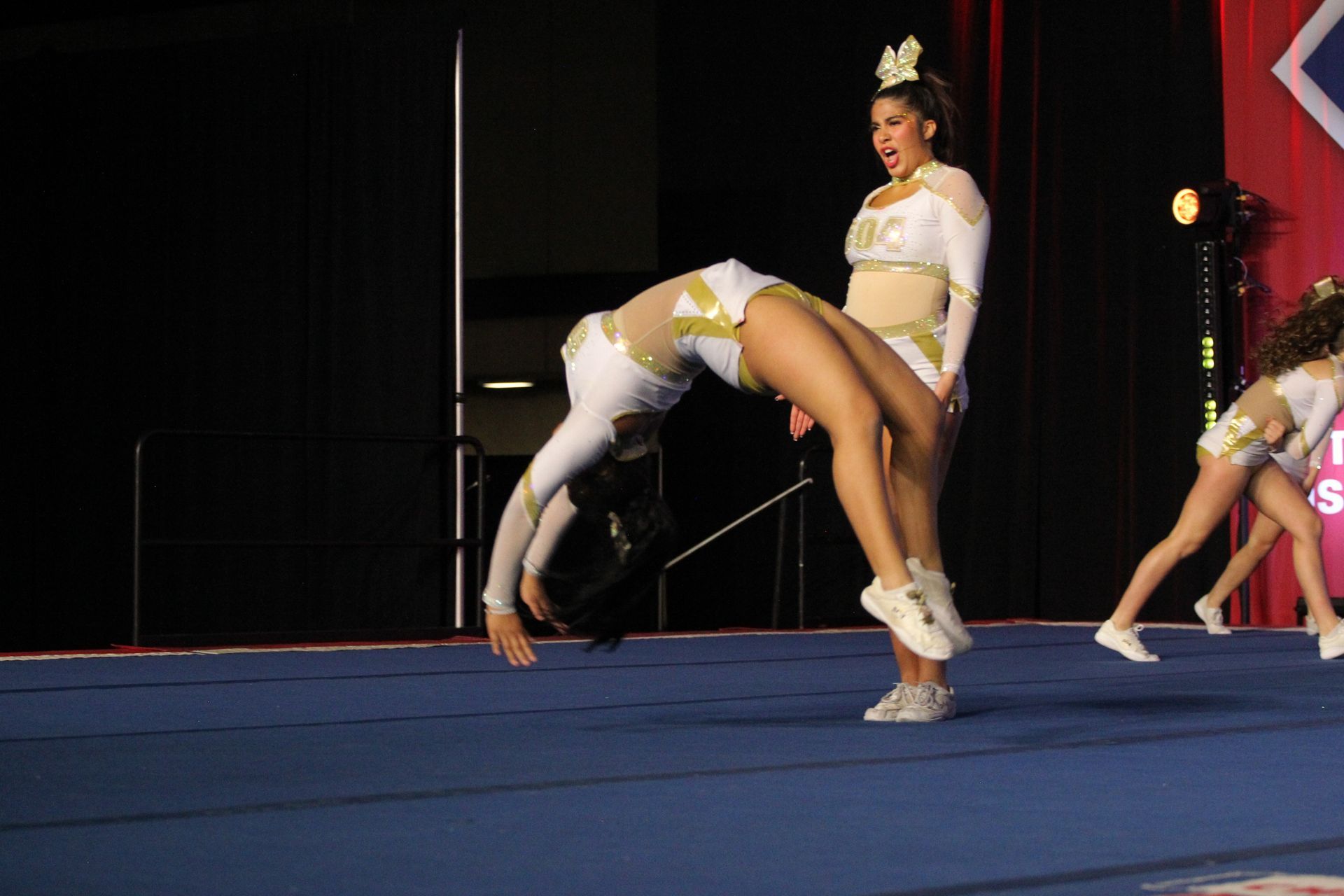 Two cheerleaders are doing a handstand on a blue mat