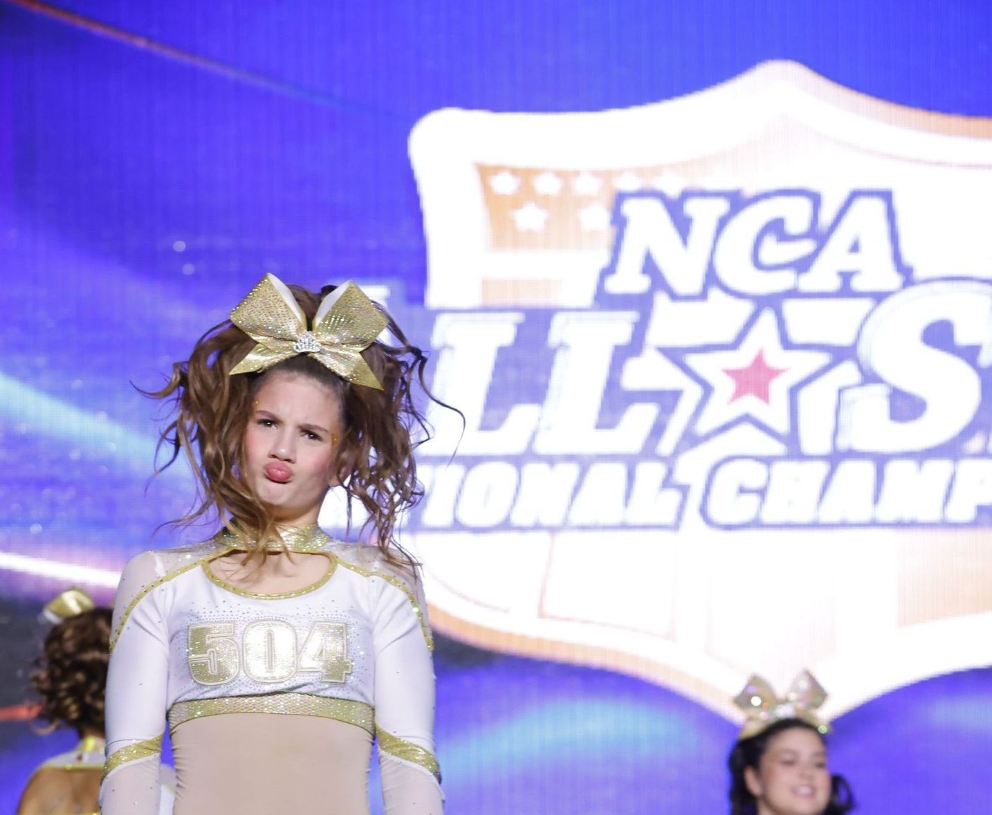 A cheerleader stands in front of a ncaa logo