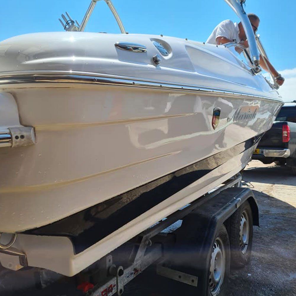 a man is sitting on top of a white boat on a trailer