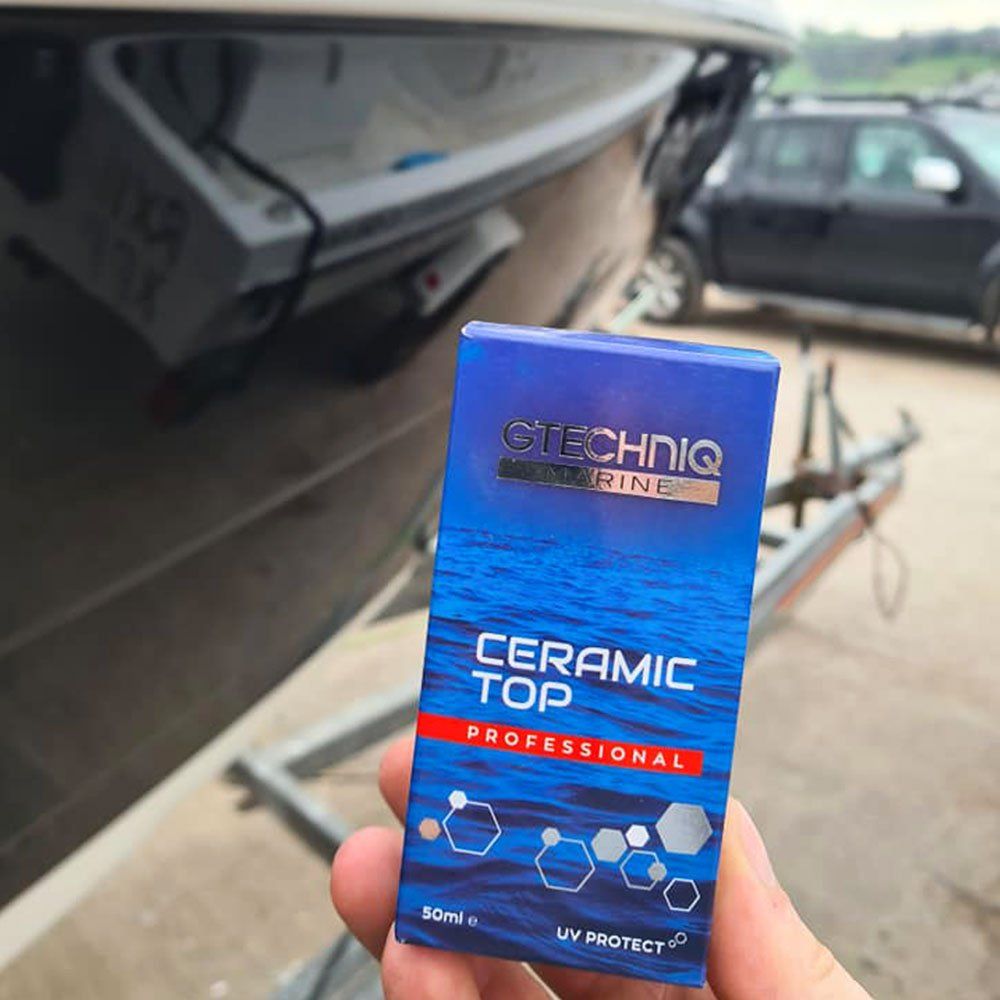 a person is holding a box of techniq ceramic top in front of a boat