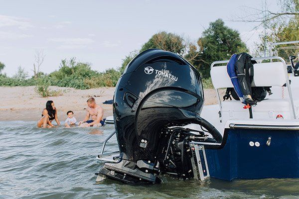 a boat engine is sitting in the water next to a beach .