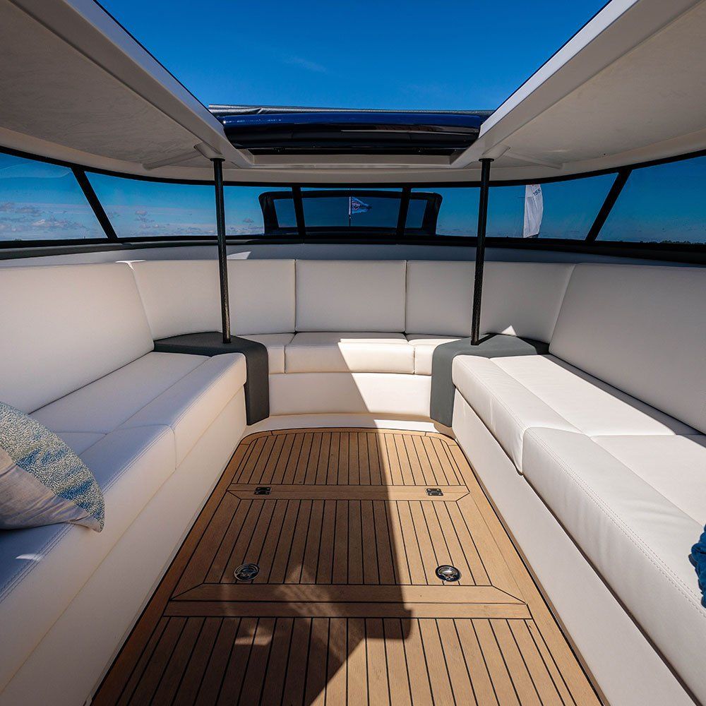 the inside of a boat with white cushions and a wooden deck