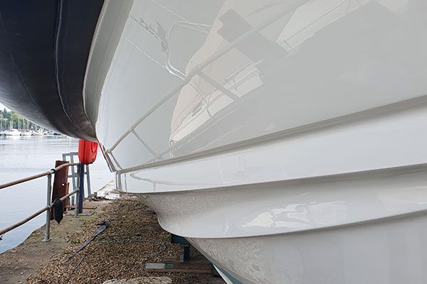 a white boat is docked next to a body of water .