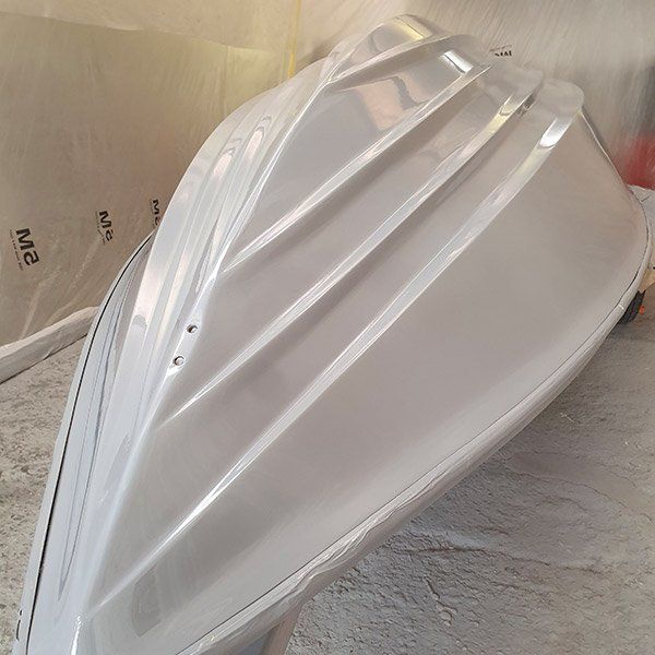 a white boat is sitting on a cement floor .