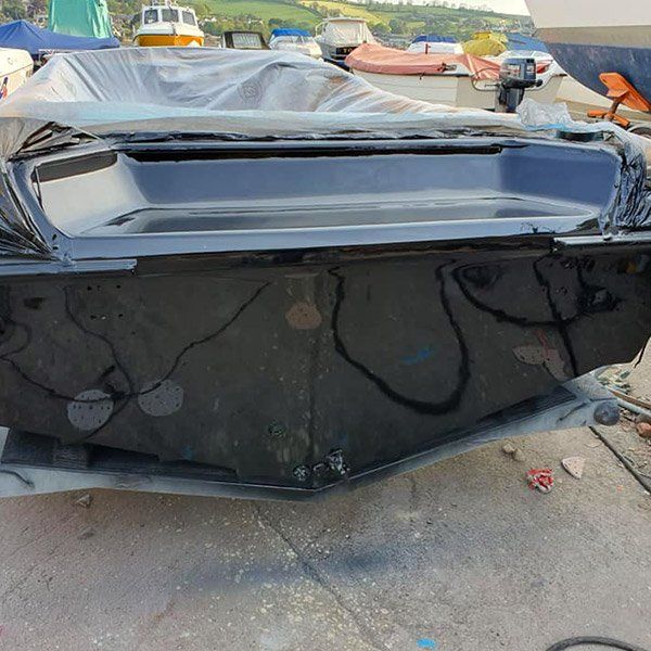 a black boat is sitting on a trailer in a harbor