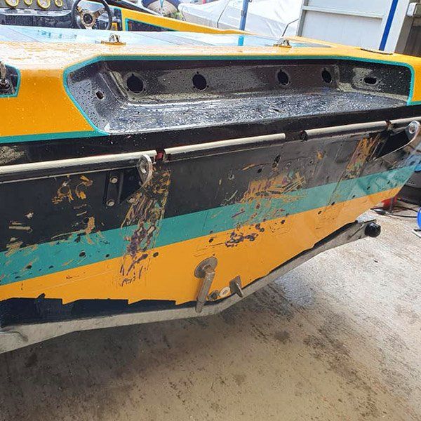 a yellow and blue boat is sitting on the ground in a garage .