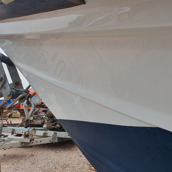 a white boat is parked next to a blue boat on a trailer