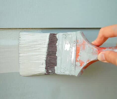Hand holding brush painting wall - Exterior Painting in Bozeman, MT
