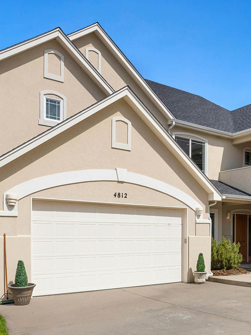 A large beige house with a white garage door