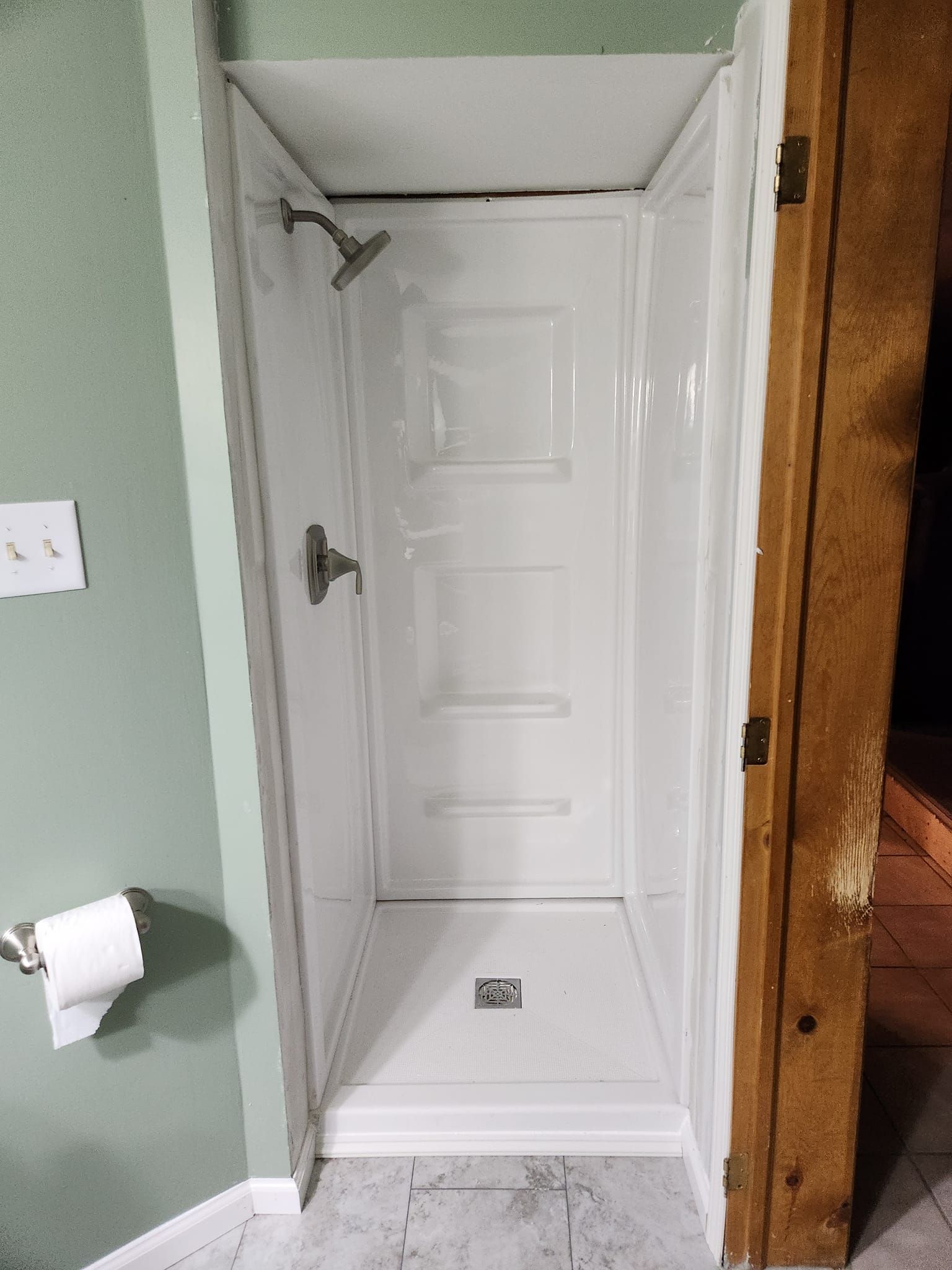 A white shower stall in a bathroom next to a door.