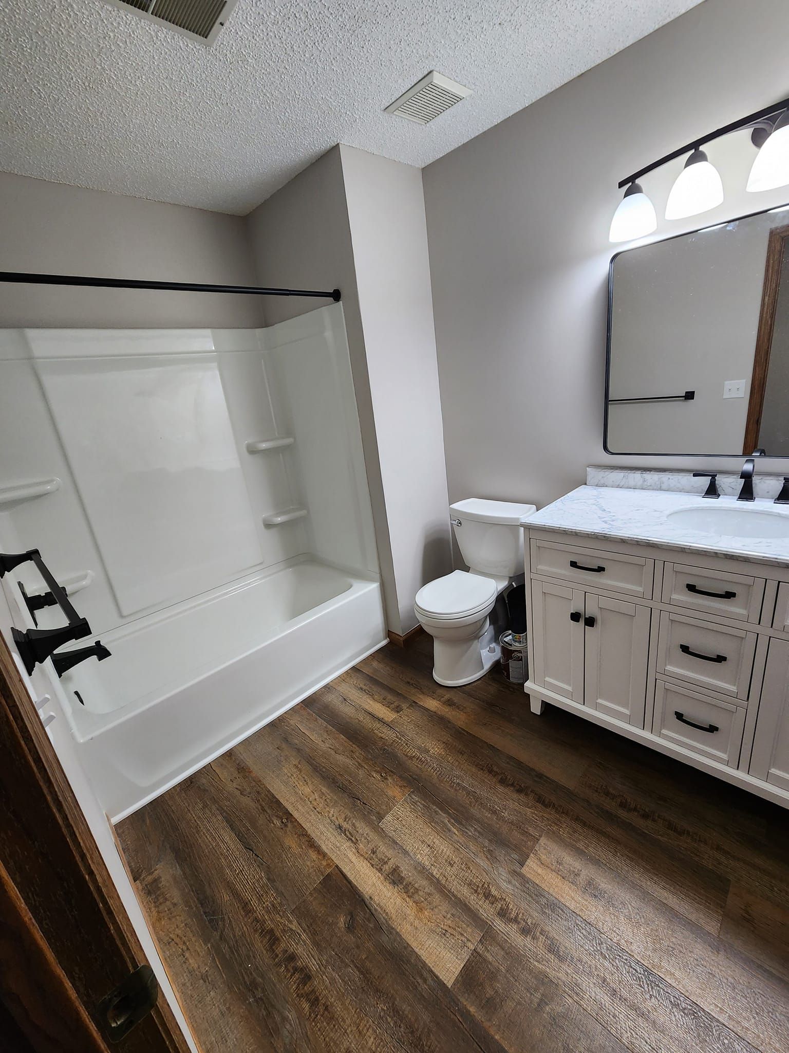 A bathroom with a toilet , sink and mirror.