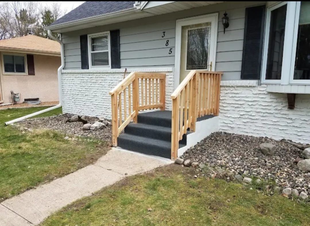 A house with a wooden porch and stairs in front of it.