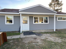 A gray house with a white door and windows