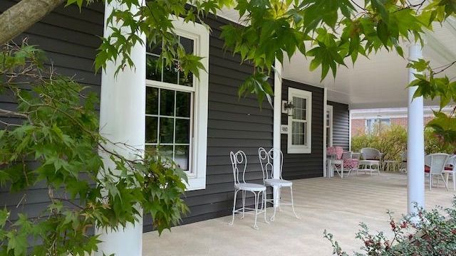 A porch with chairs and a tree in the background