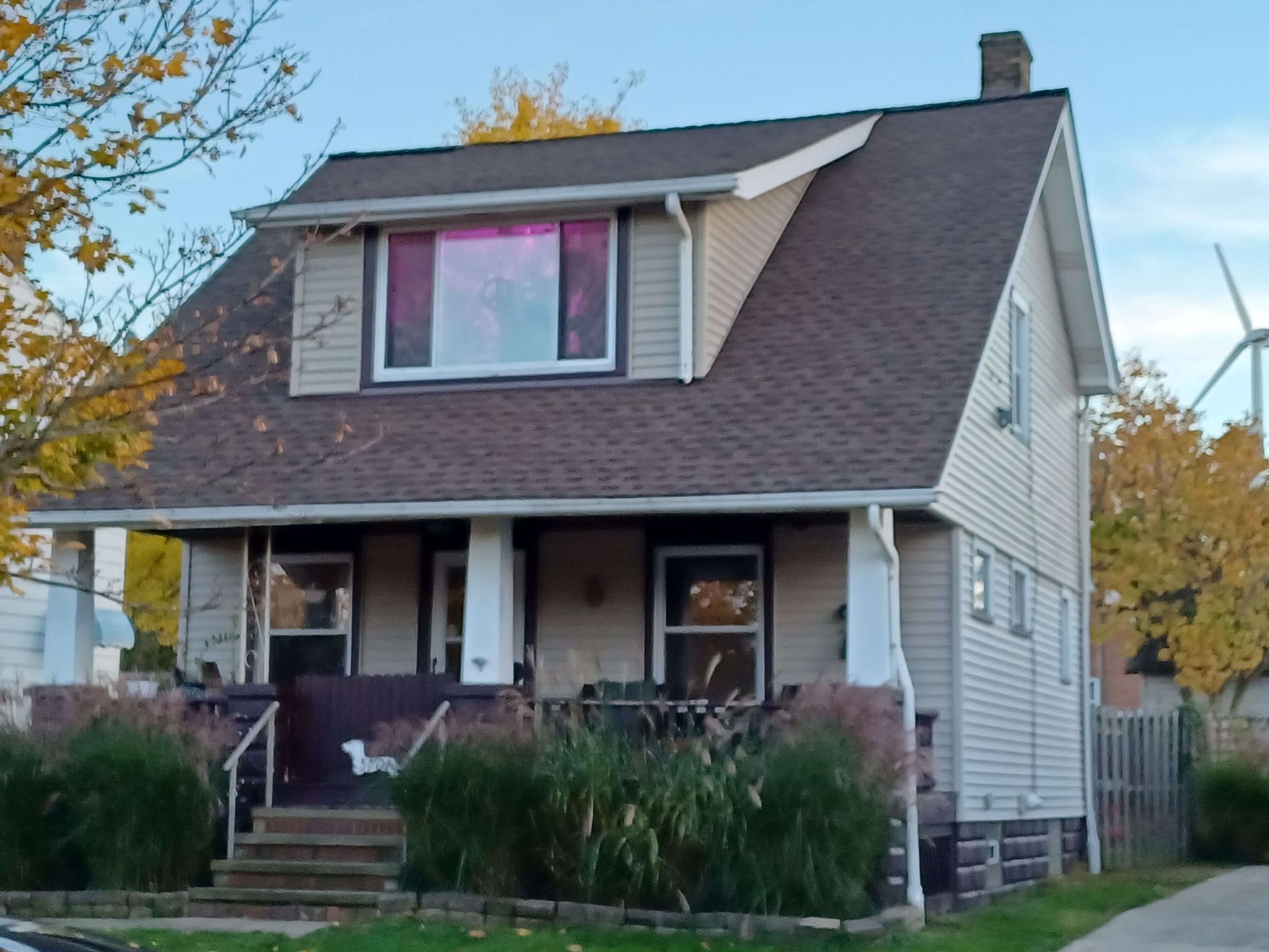 A house with a wind turbine in the background