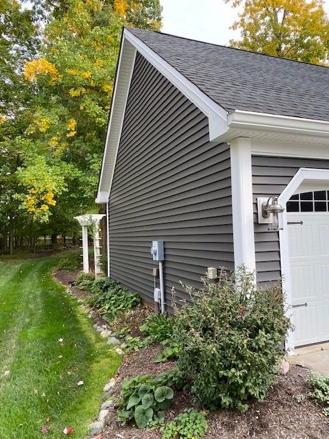 A house with a gray siding and a white garage door.