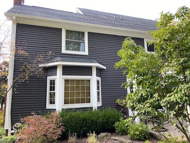 A black house with white trim and a bay window.