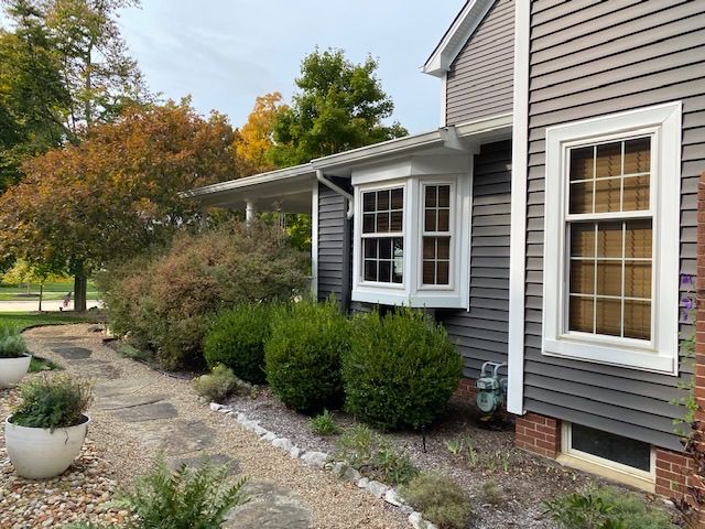A house with a lot of windows and bushes in front of it.