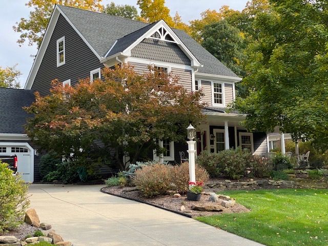 A large house with a driveway and a garage is surrounded by trees.