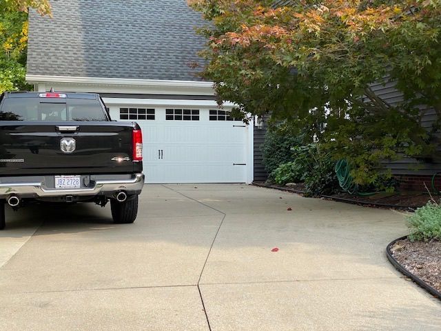 A black truck is parked in a driveway in front of a garage door.