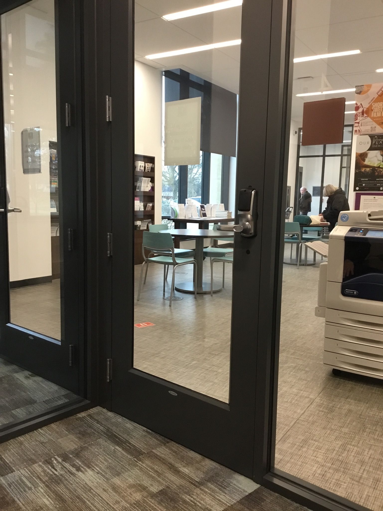 A glass door is open to a room with tables and chairs.