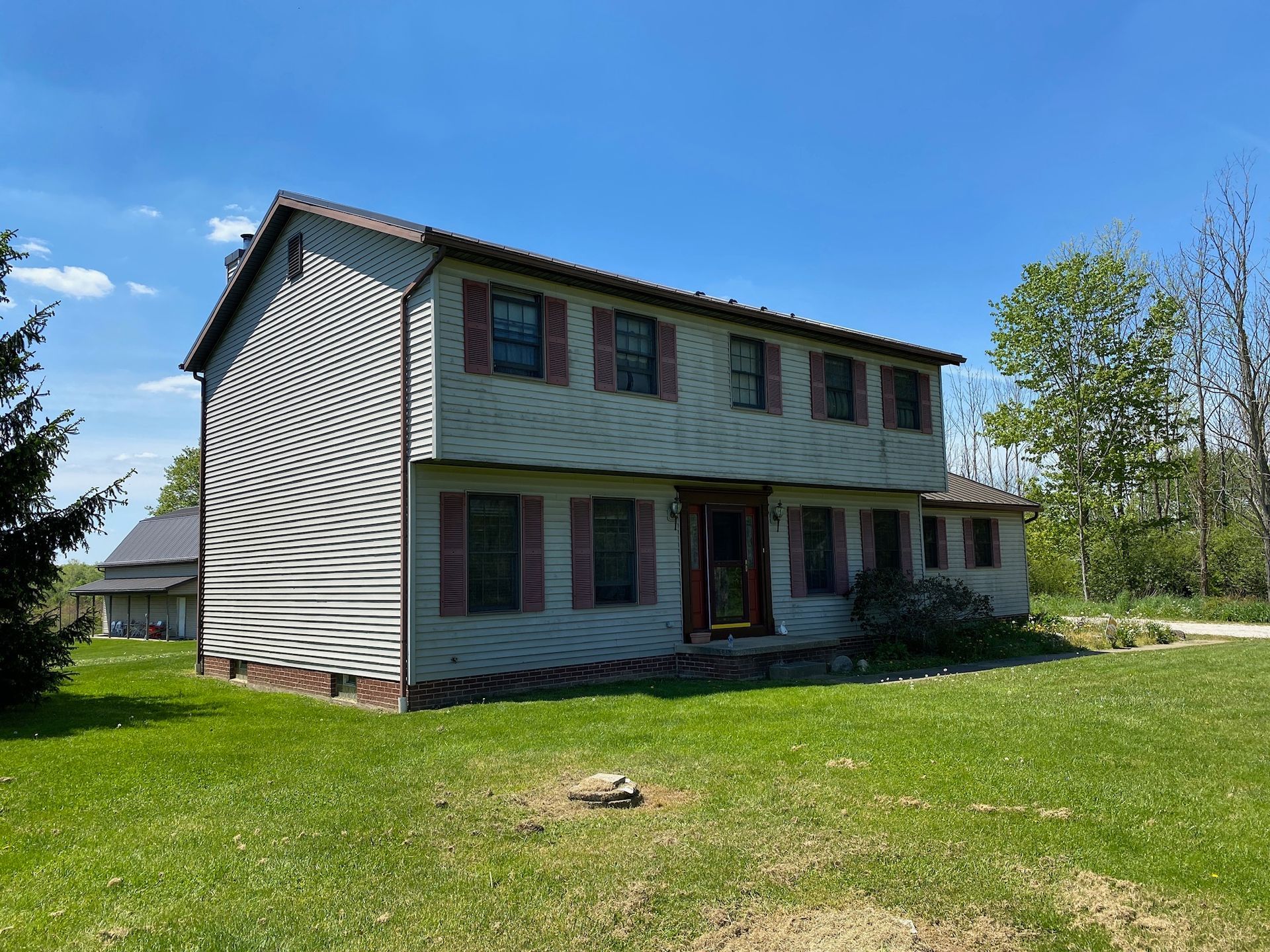 A large house with a lot of windows is sitting on top of a lush green field.