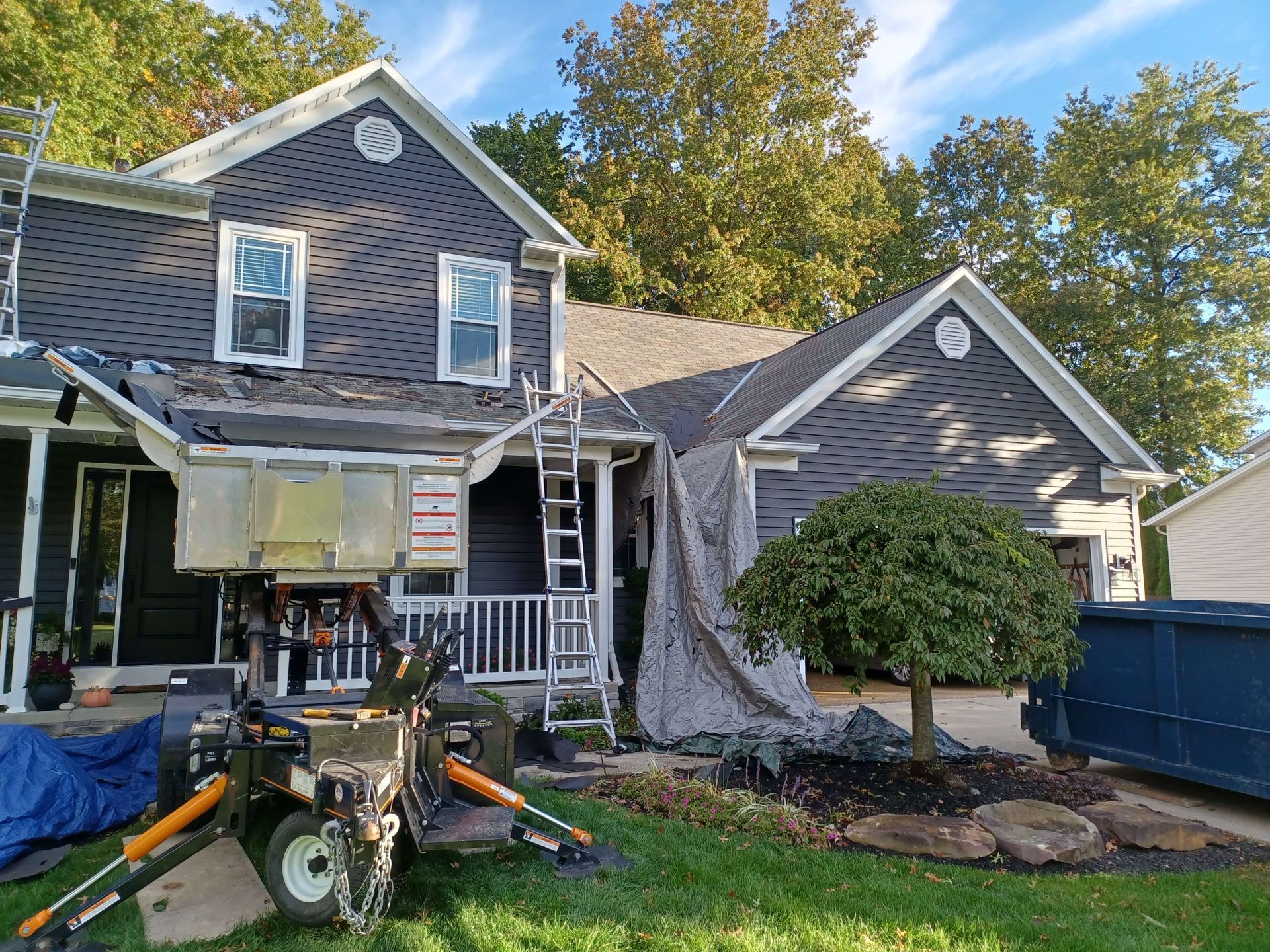 A house is being painted and a lawn mower is parked in front of it.