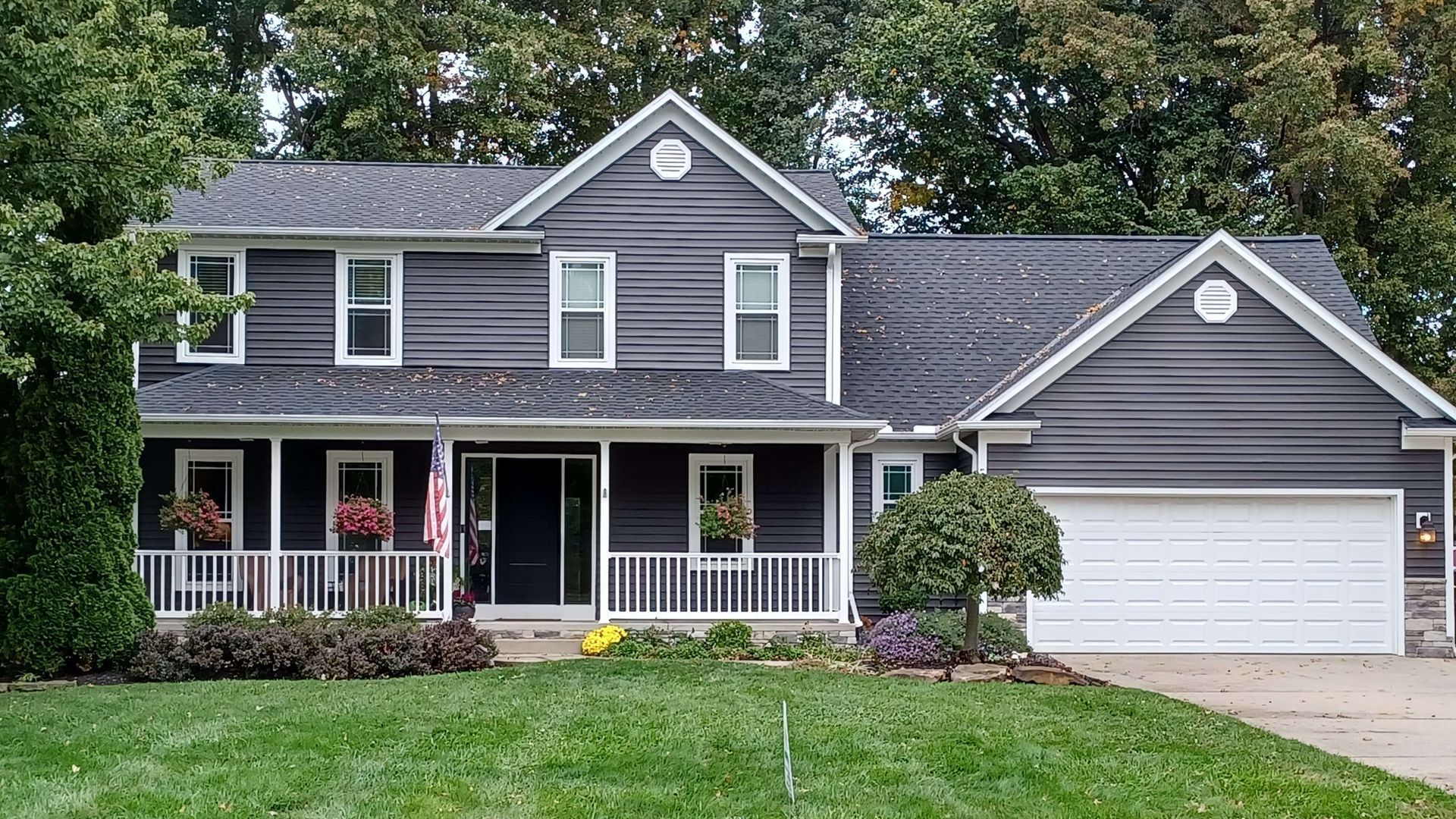 A large house with a black siding and a white garage door.