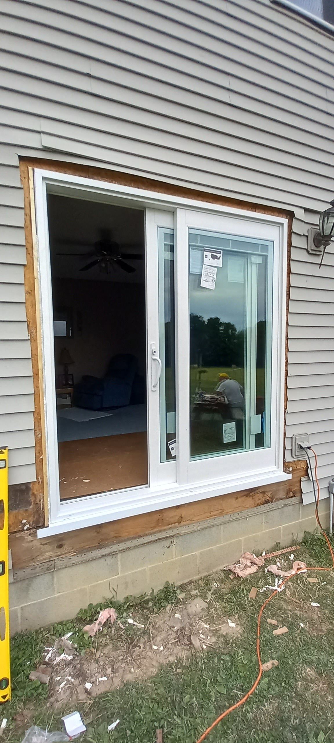 A sliding glass door is being installed on the side of a house.