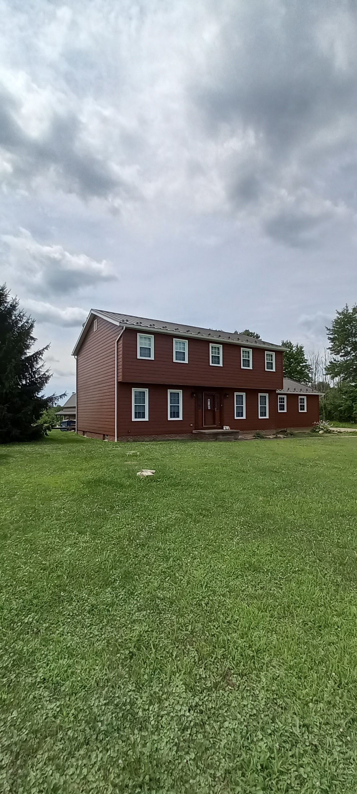 A red brick house is sitting in the middle of a lush green field.