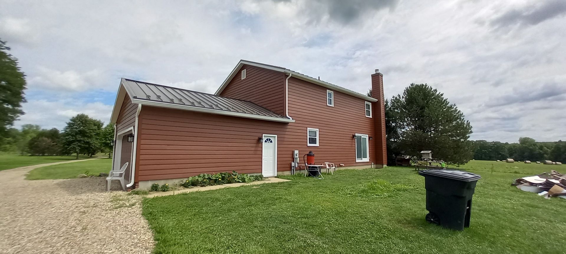 A large red house is sitting in the middle of a grassy field.
