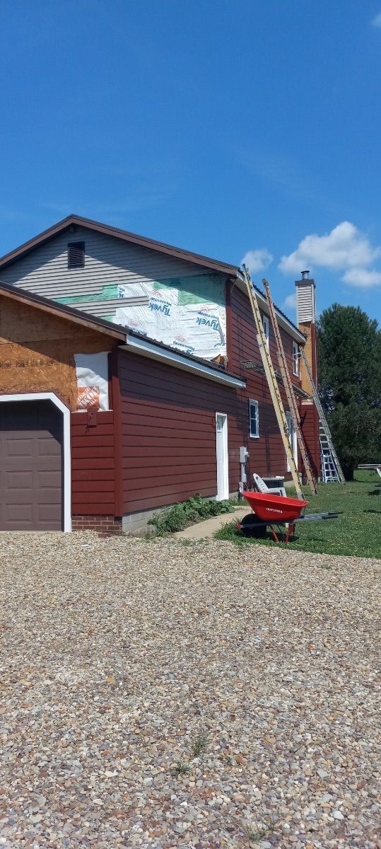 A red wheelbarrow is parked in front of a house under construction.