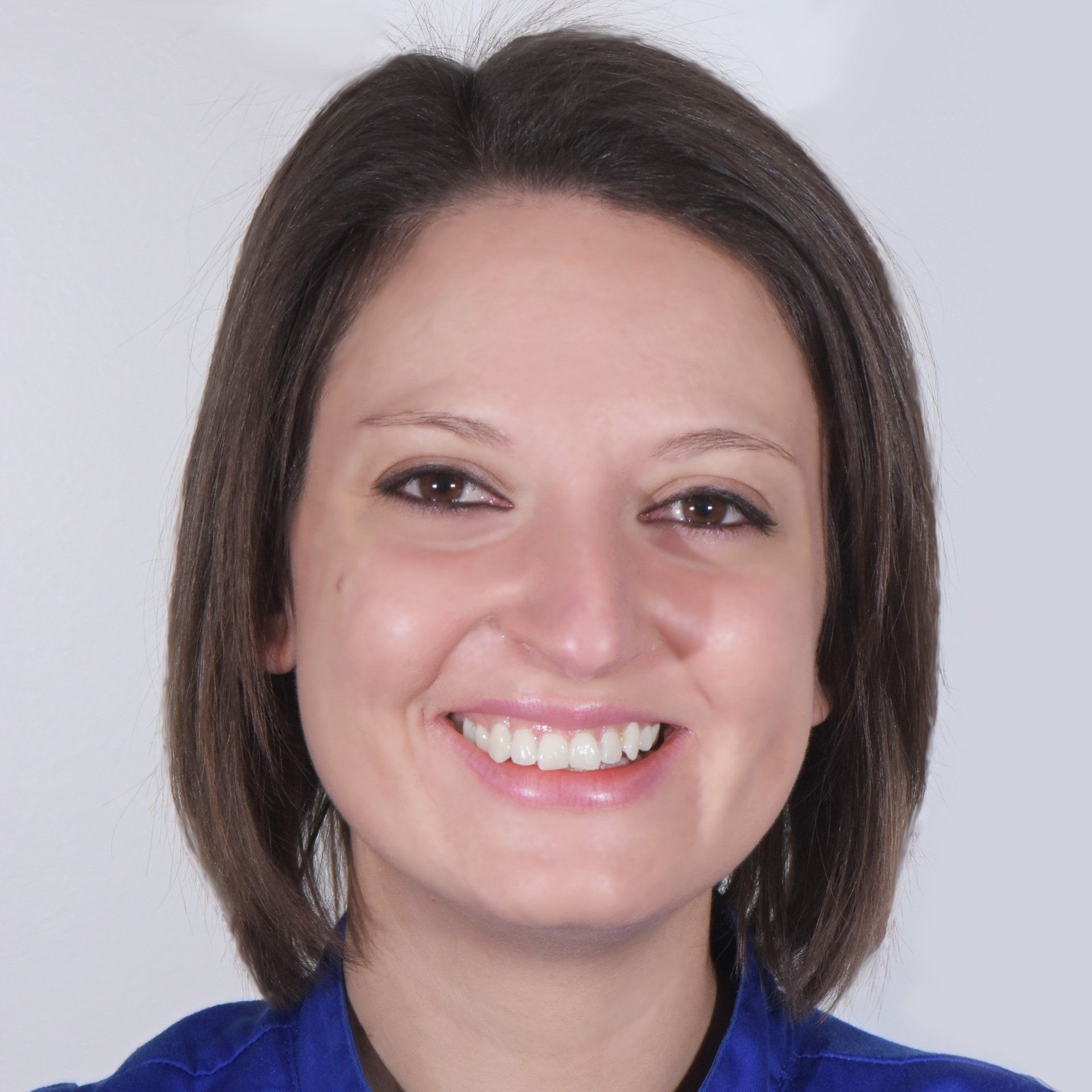 Donna sorridente con capelli castani corti che indossa una maglietta blu.