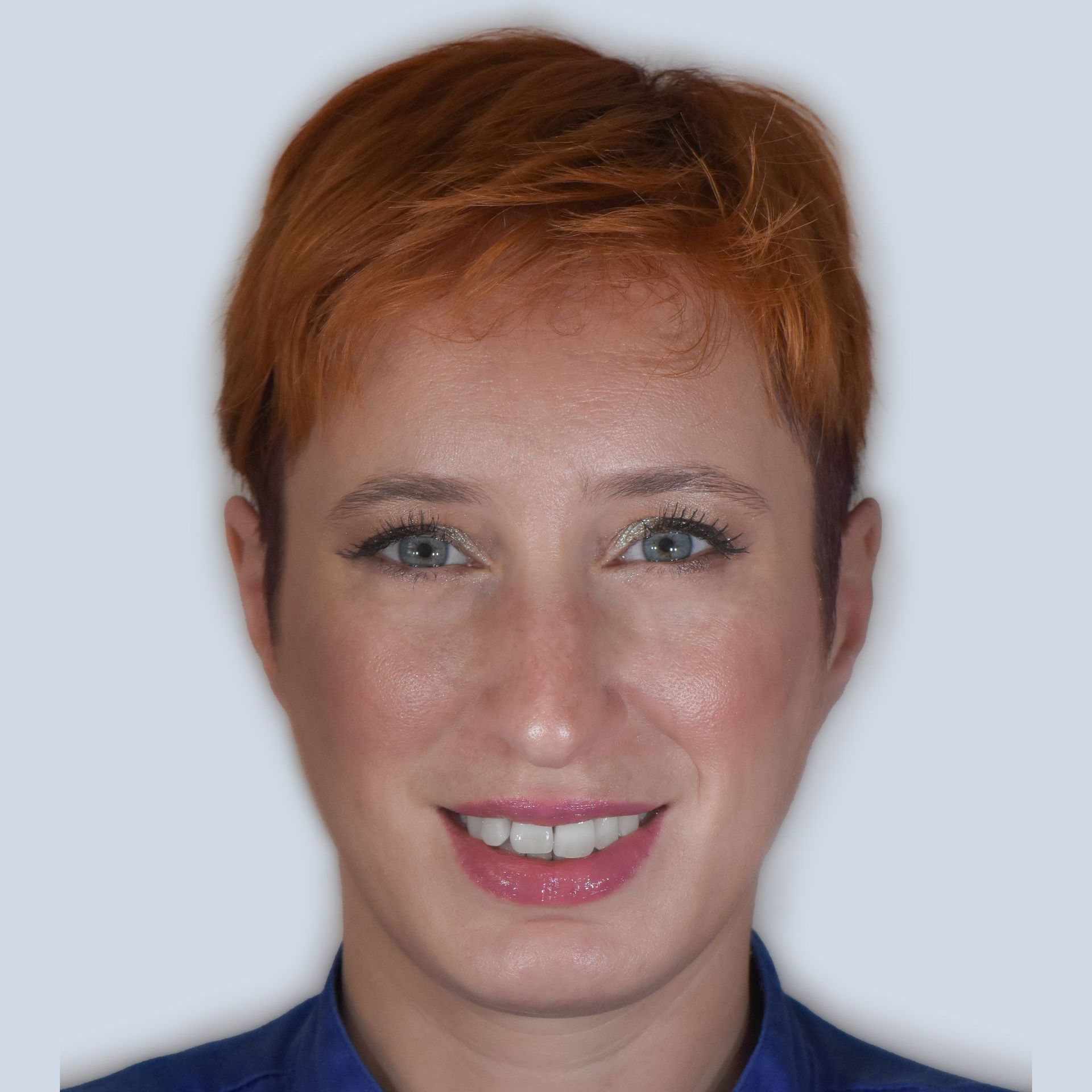 Donna con i capelli rossi corti, sorride direttamente alla telecamera. Ha gli occhi azzurri e indossa una maglietta blu.