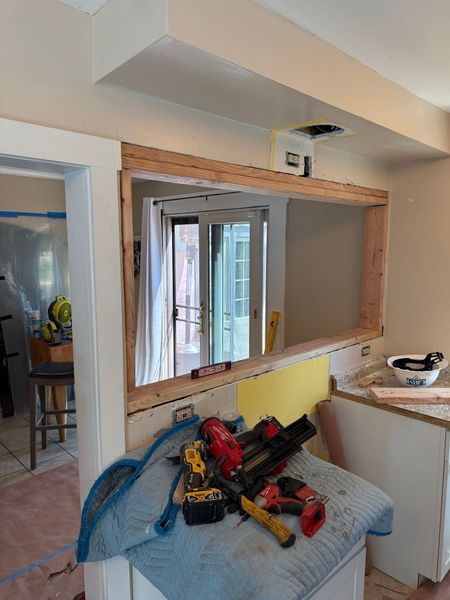 Construction in a kitchen: doorway with newly framed opening. Tools on a countertop. French doors in the background.