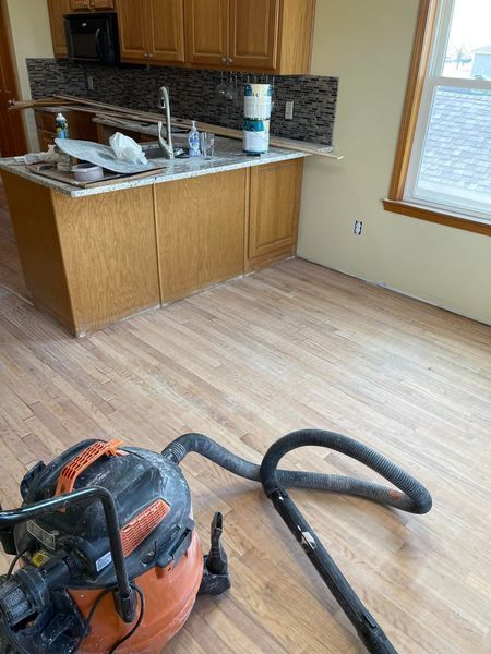 Kitchen with hardwood floors being renovated, with cabinets, island, and a shop vacuum.