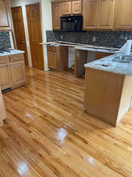 Kitchen with hardwood floors, light wood cabinets, and unfinished countertop area; doors in background.