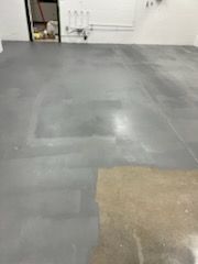 Gray concrete floor with a lighter patch and some equipment in the background.