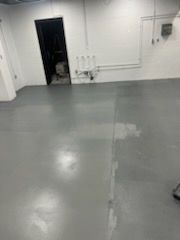 Empty, freshly painted gray room with a dark doorway and white walls.