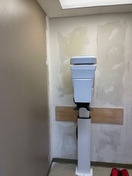 Toilet mounted on a white pedestal in a bathroom with unfinished walls.