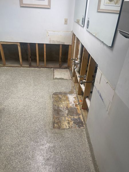 Bathroom with exposed wall studs and flooring damage, likely due to water.