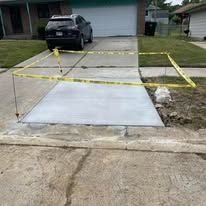 Newly poured concrete driveway section surrounded by yellow caution tape.