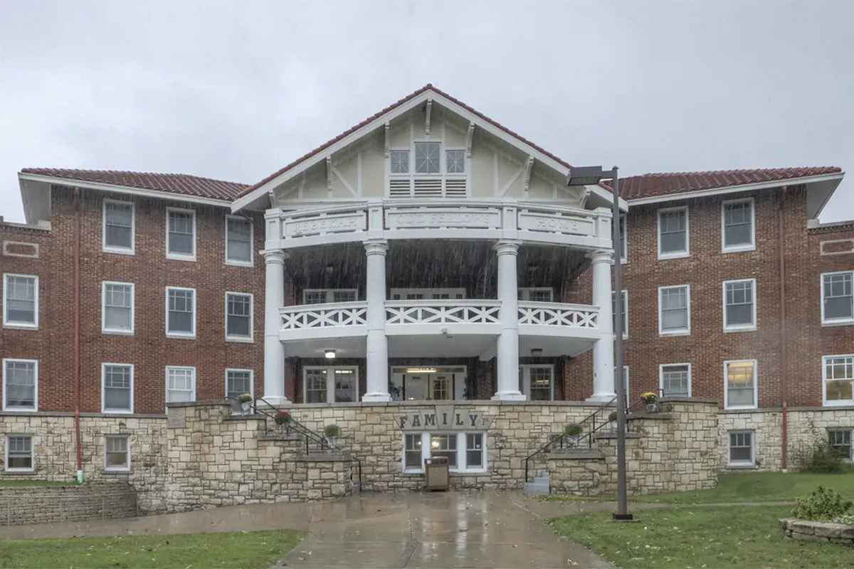 Modern kitchen with light green cabinets, wood island, stainless steel appliances, and pendant lights.