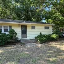 Yellow house with green trees in front.