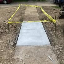 New concrete walkway section, marked with yellow caution tape.