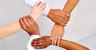 Four hands of different skin tones clasped together in unity.