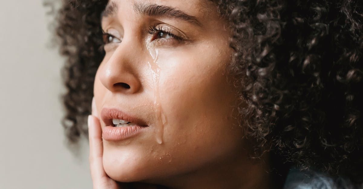 A woman with curly hair is crying with tears running down her face.