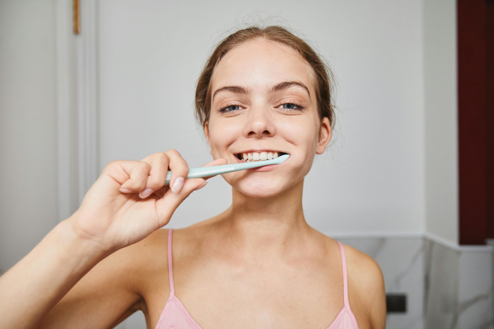 A woman is brushing her teeth in a bathroom.