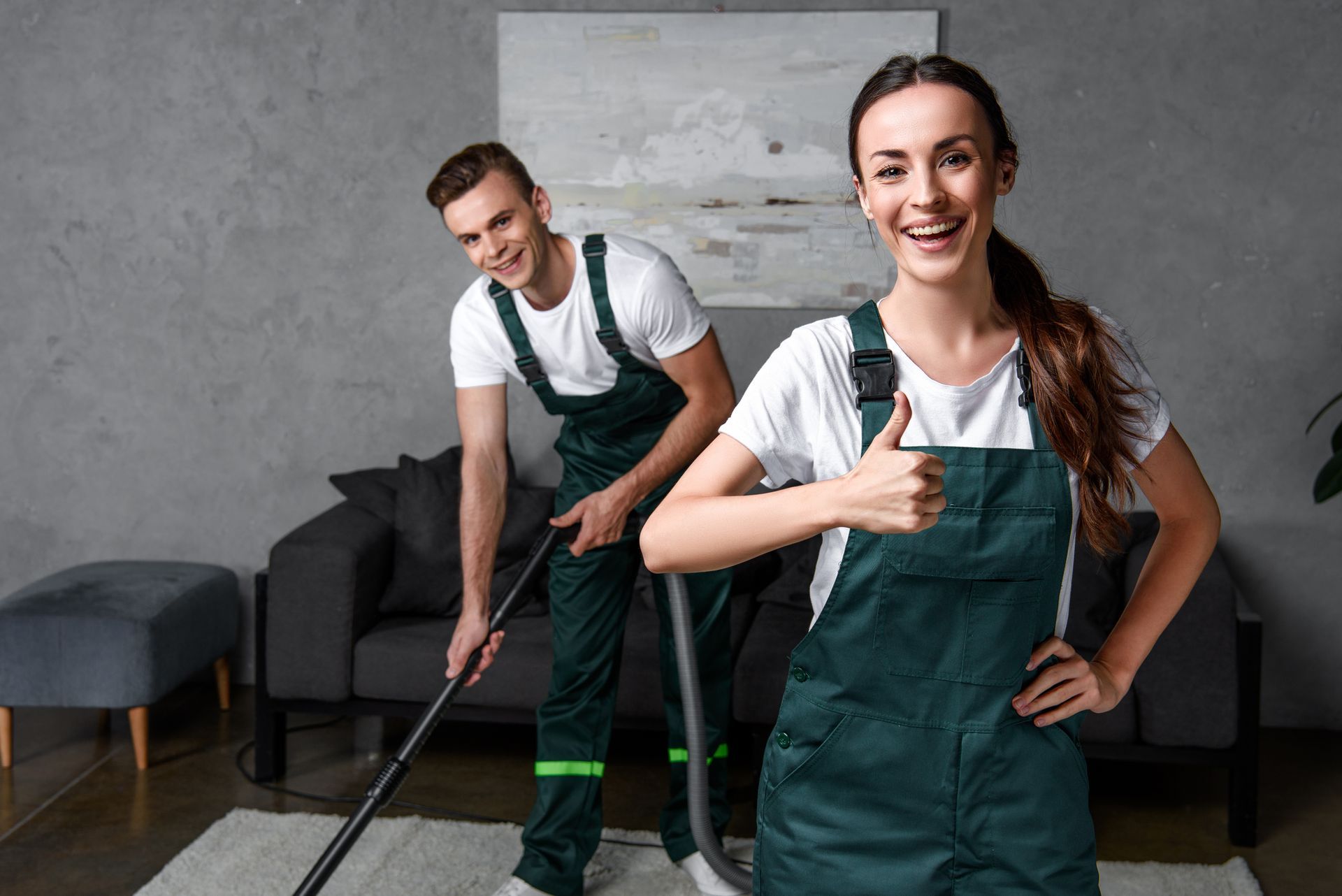 A person and person in green overalls holding vacuum cleaners | Building Cleaning Services Nashville