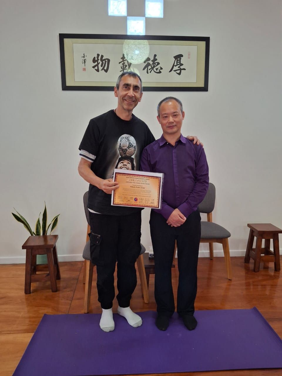 Dos hombres de pie en el interior, uno de ellos con un certificado.